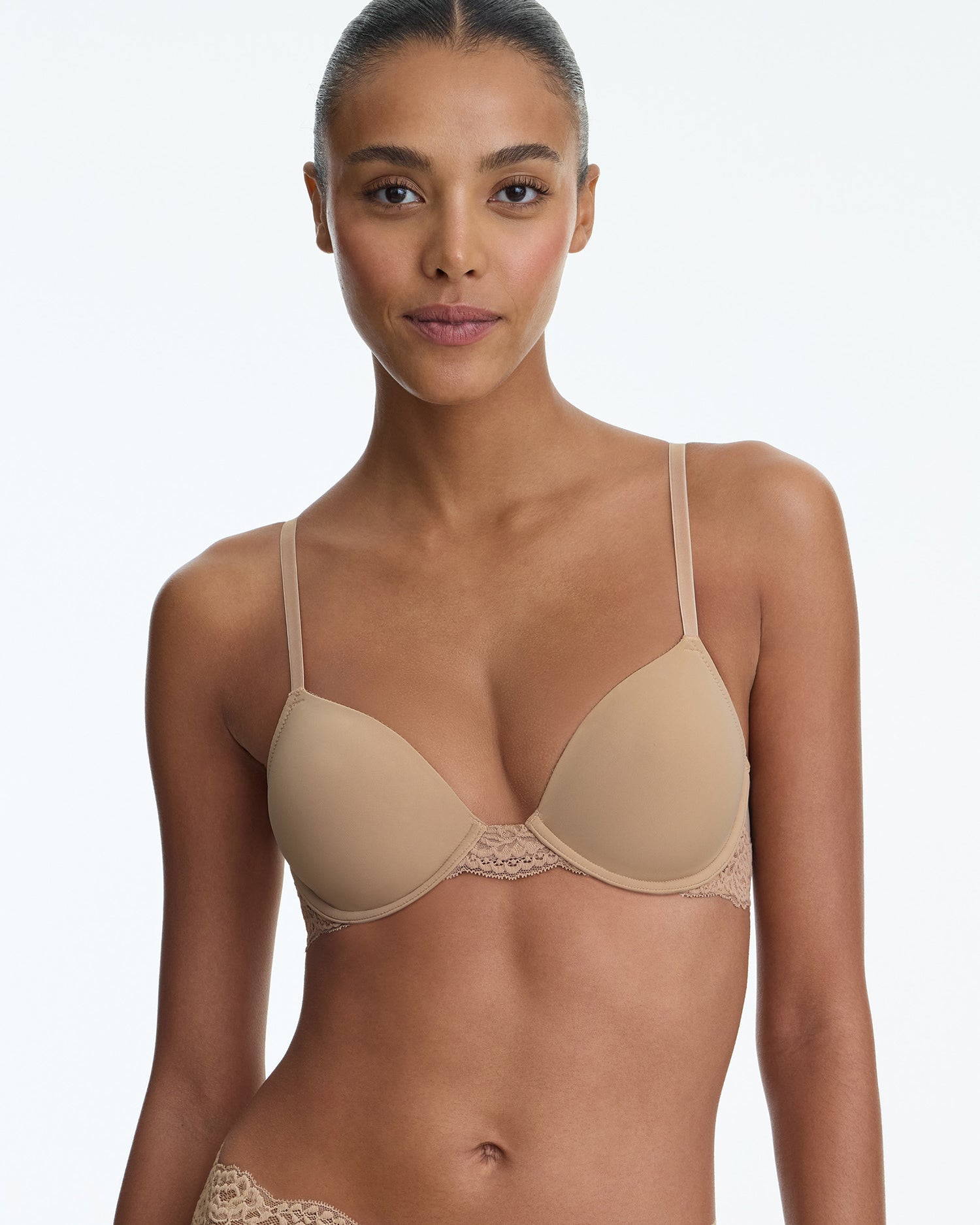 Woman wearing a beige bra and panties set on a plain background
