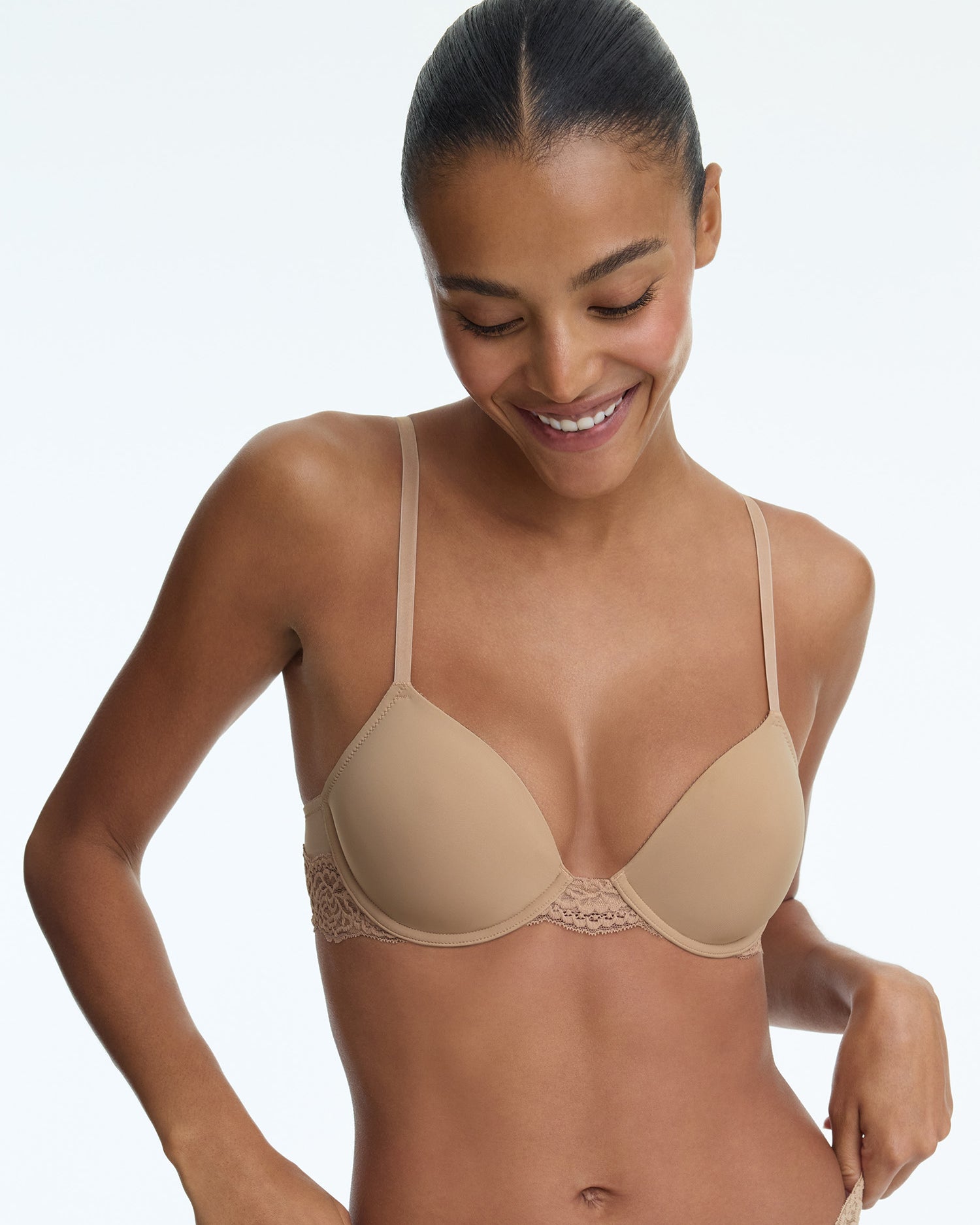 Woman wearing a beige bra against a plain background