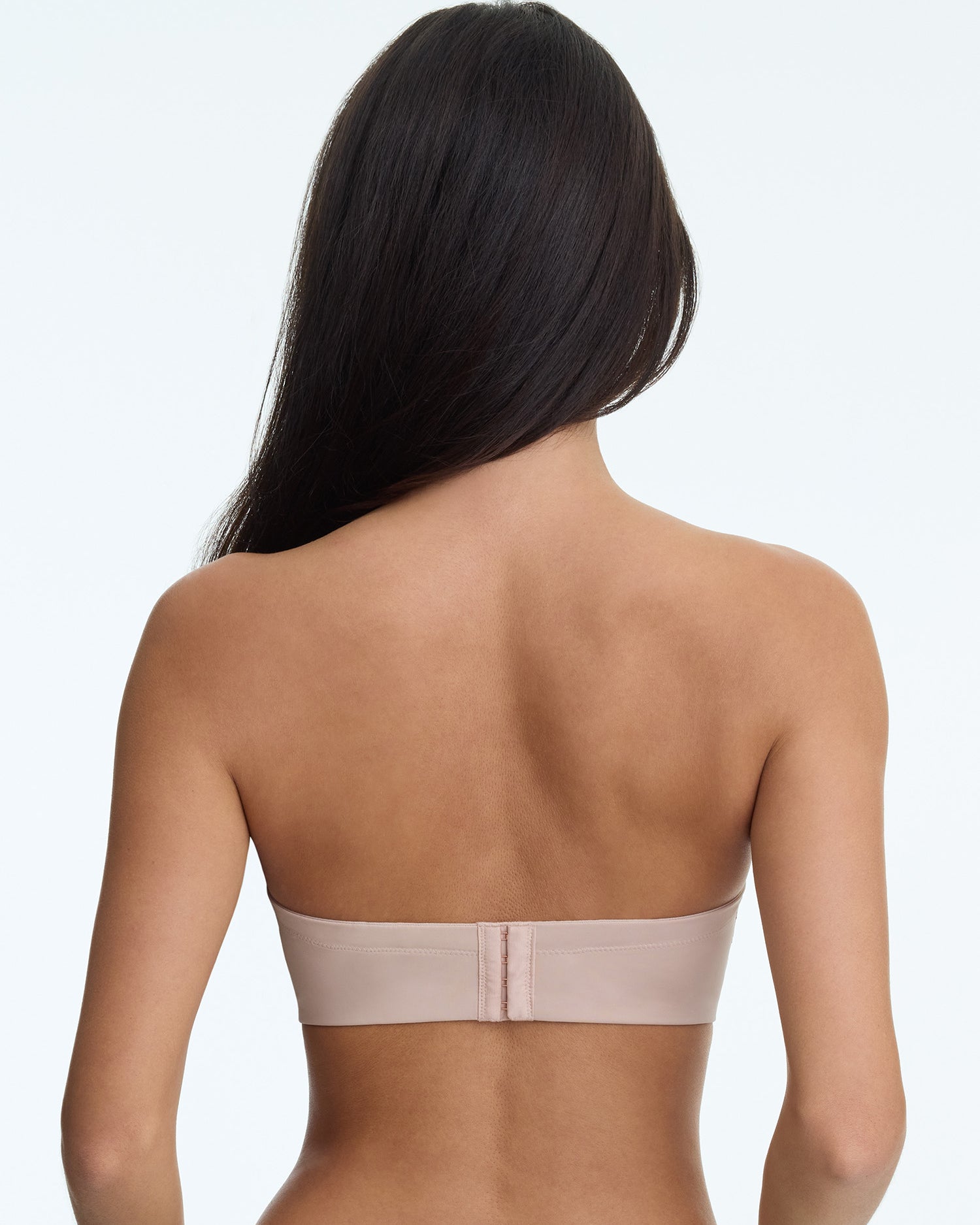 Woman wearing a beige strapless bra on a white background