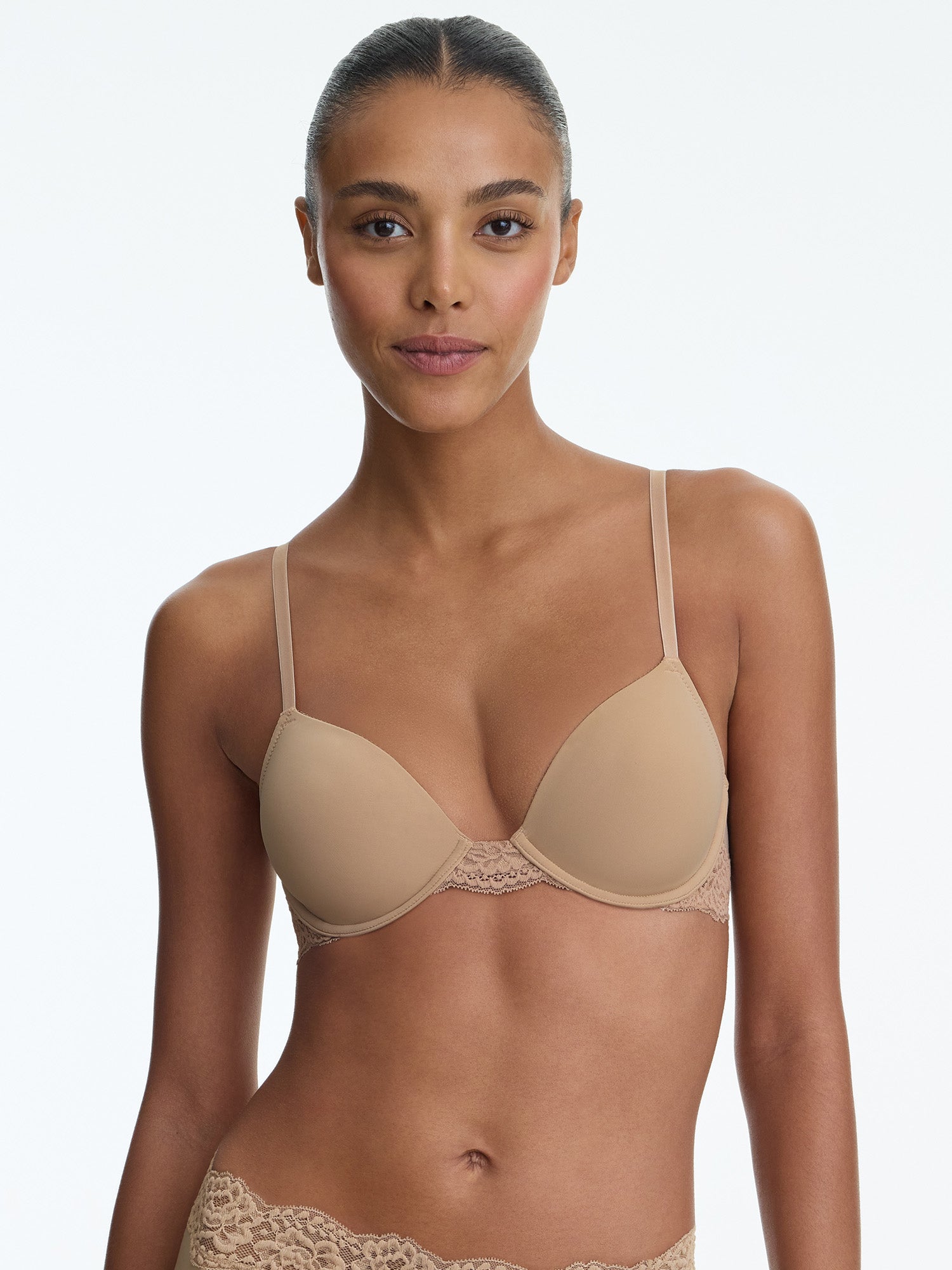 Woman wearing a beige bra and panties set on a plain background