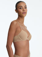 Woman wearing a beige bralette on a white background