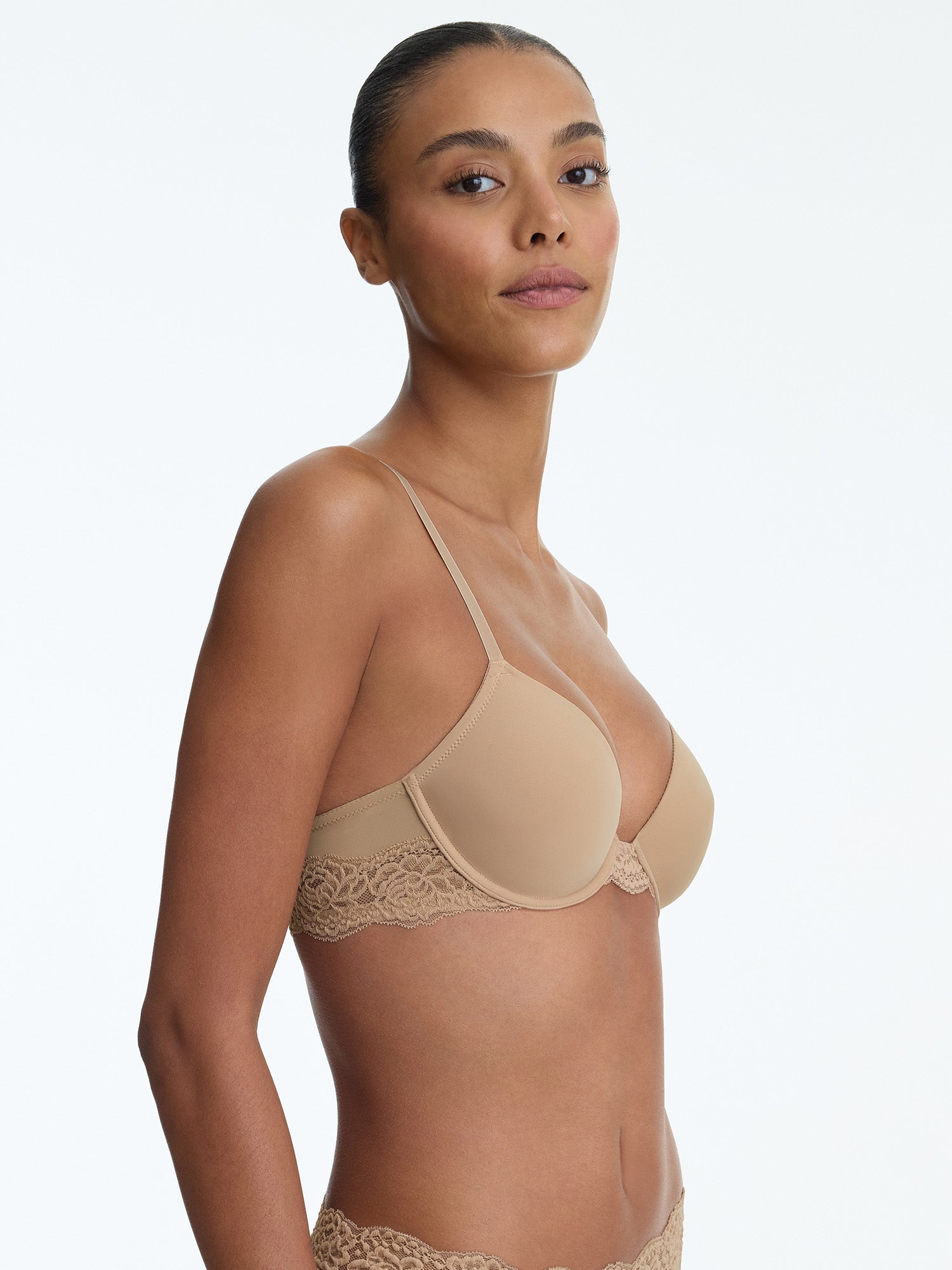 Woman wearing a beige bralette on a white background