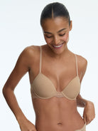Woman wearing a beige bra against a plain background