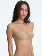 Woman wearing a beige bra with lace details on a plain background