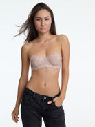 Woman wearing a strapless lace bra and black jeans on a white background