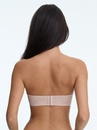 Woman wearing a beige strapless bra on a white background